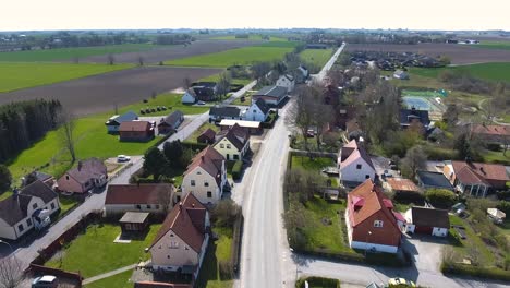 Luftaufnahme-Einer-Kleinen-Ländlichen-Stadt-Namens-Löderup-In-Südschweden-Skåne-Mit-Einem-Fliegenden-Vogel-Und-Einem-Auto,-Das-Auf-Der-Straße-Fährt