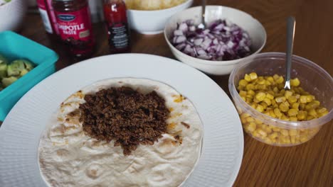 Panning-and-tilting-view-of-some-ground-taco-meat-laying-on-a-tortilla-bread
