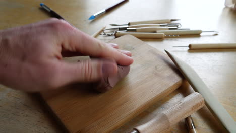 Ein-Künstlerstudent,-Der-In-Einem-Kunstatelier-Mit-Werkzeugen-Auf-Dem-Tisch-Mit-Weichem-Braunem-Modellierton-Modelliert,-Ihn-Mit-Seinen-Händen-Und-Fingern-Drückt-Und-Formt