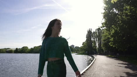 Beautiful-Italian-girl-walking-peacefully-and-in-a-tranquil-park-wearing-a-shimmery-sweater-in-London,-United-Kingdom
