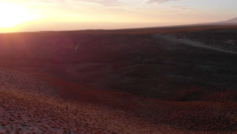 Aerial-cinematic-shot-going-over-a-valley-at-sunset-in-the-Atacama-Desert,-Chile,-South-America