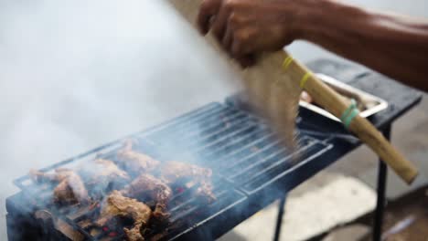 Slow-Motion-shot-of-an-Asian-street-vendor-cooking-Ayam-Bakar-on-a-smoky-grill
