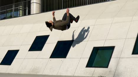 Slow-motion-shot-of-a-young-parkour-athlete-doing-a-wall-backflip-in-an-urban-environment