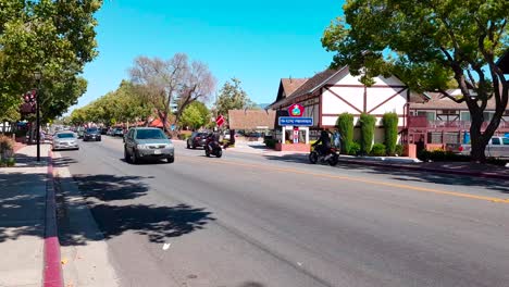 Walking-shot-on-Mission-Drive-in-Danish-styled-city-of-Solvang-with-The-King-Frederik-on-the-other-side-of-the-road-in-Solvang,-California,-USA