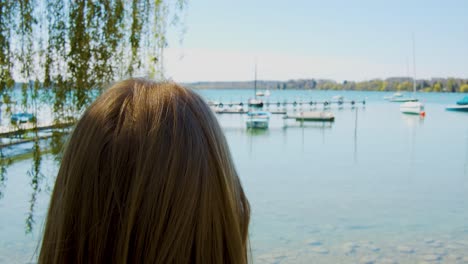 Blond-woman-is-standing-in-front-of-a-picturesque-lake