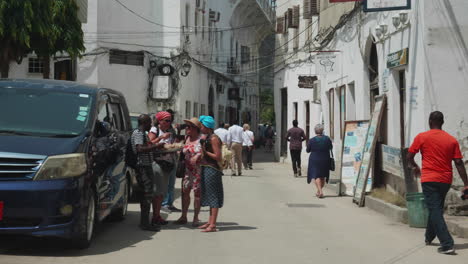 Tourists-and-locals-walking-in-the-street-of-Stone-Town,-Zanzibar-island