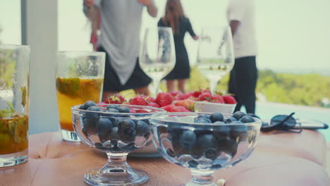 Verschwommener-Hintergrund-Mit-Tanzenden-Männern-Und-Frauen-Und-Spaß-In-Der-Poolvilla-Mit-Getränken,-Cocktails-Mit-Erdbeeren-Und-Blaubeeren-Im-Vordergrund