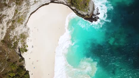 Drone-shot-gliding-over-the-beautiful-KelingKing-Beach-with-it's-Turquoise-blue-water-and-large-waves-crashing-on-the-shore