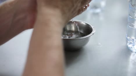 Close-up-Shot-of-a-person-cleaning-their-hands-in-a-bowl-of-water-prior-to-eating-a-meal-with-their-hands