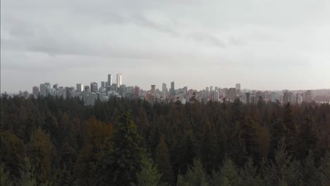 Vancouver-City-Skyline-Revealed-Above-The-Trees-in-Stanley-Park-Rising-Aerial-Drone-Shot