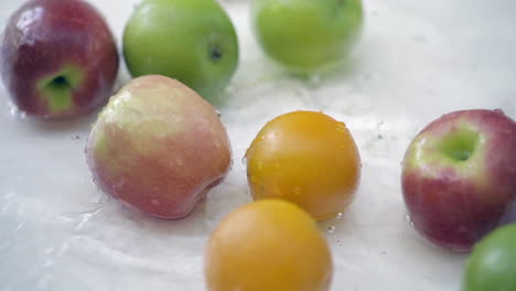 Slomo-Von-Äpfeln-Und-Orangen-Im-Wasser-Auf-Weißem-Hintergrund