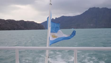 Langsame-Aufnahme-Der-Argentinischen-Flagge-Im-Argentinischen-See,-Die-Sich-Auf-Einem-Boot-Bewegt