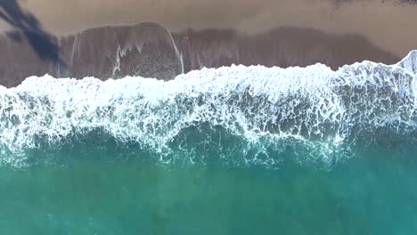 Aerial-view-waves-crashing-on-tropical-beach-sand