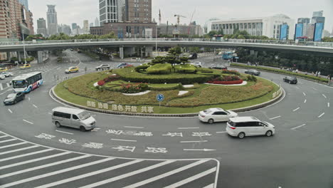 Time-lapse-of-a-circle-intersection-with-cars,-buses-passing-under-an-elevated-walkway-in-Luziazui-area-of-Shanghai,-China