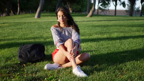 Beautiful-young-hispanic-college-student-resting-on-a-grassy-park-field-between-classes-on-campus