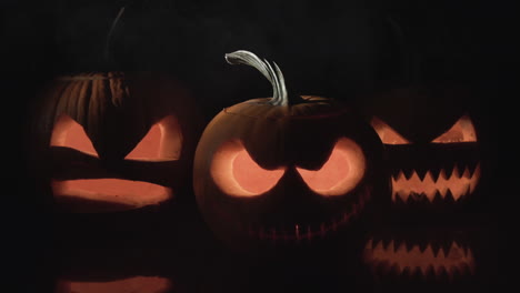 Three-halloween-pumpkins-on-black-background-with-smoke-puff,-Apple-Pro-Res