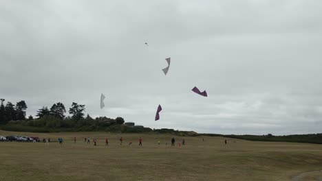 Four-people-flying-highly-maneuverable-stunt-kite-in-coordination-on-a-cloudy-windy-day-in-a-grass-field-at-Fort-Casey