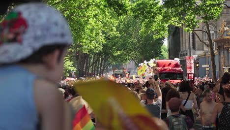 Young-child-holding-a-Gay-Pride-flag-is-watching-the-march-pass-by-him-in-Paris,-France