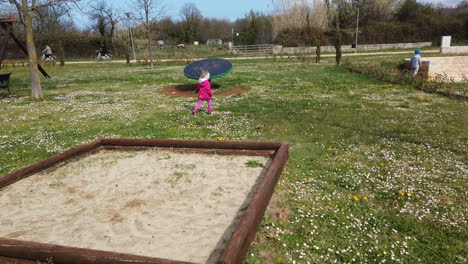 Young-Girl-Leaving-Sand-Pit-In-Park-Before-Running-Off-On-The-Grass