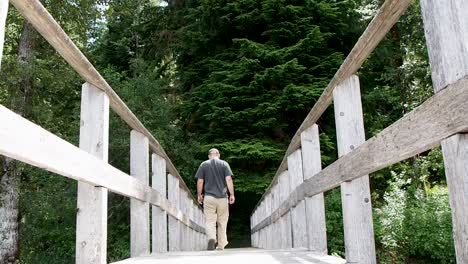 Man-on-wooden-dock-on-a-lake-walking-in-to-the-forest