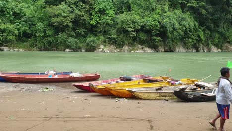 Barquero-Paseando-Por-Varios-Barcos-Atracados-En-La-Orilla-Del-Río,-Vida-Rural