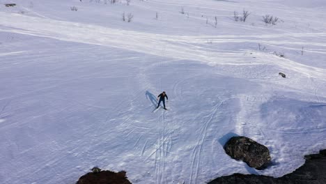 Aerial-view-of-man-on-skis-walking-up-snowy-hill