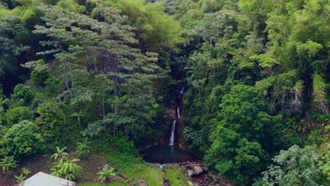 Epische-Luftaufnahmen-Von-Wasserfällen-Im-Regenwald-Von-Grenada-Mit-Häusern-Im-Vordergrund-Und-Bergen-Im-Hintergrund