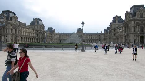 Turistas-Caminando-Frente-A-La-Fachada-Del-Museo-Del-Louvre,-En-París,-Francia