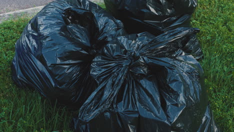 Pile-of-black,-plastic-garbage-bags-put-out-on-the-curb-for-collection