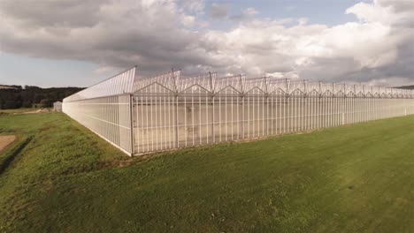Aerial-view-of-an-greenhouse-near-a-field-with-blu-sky-on-a-sunny-day