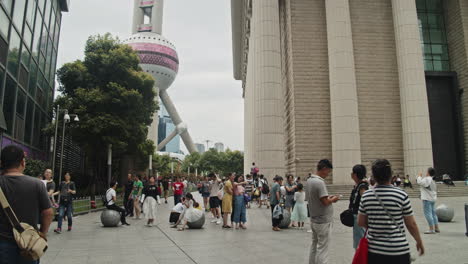 Tourists-walking-around-and-taking-pictures-near-futuristic-Oriental-Pearl-TV-Tower,-Shanghai,-China