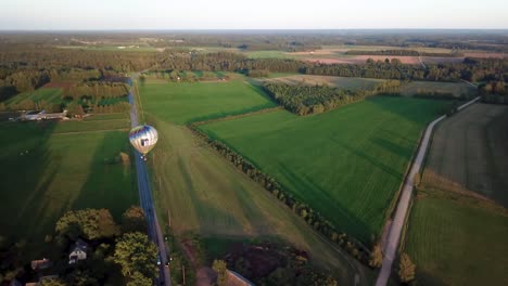 Long-shadows-extend-over-the-lush-farmland-of-Valmiera,-Latvia-as-a-Hot-Air-Balloon-drifts-silently-along