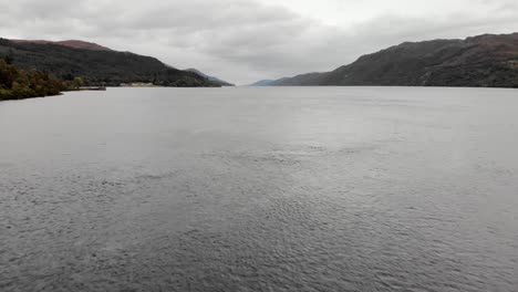 Flying-low-over-choppy-Loch-Ness-water-on-gray-day,-Scotland,-aerial