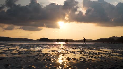 Caucasian-family-playing-on-Ao-Nang-beach-as-the-sun-sets,-spending-time-as-a-family-on-a-vacation-holiday-to-Krabi-Thailand