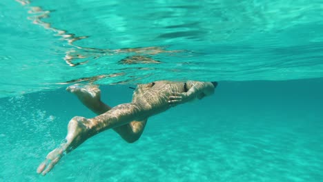 Underwater-shot-of-woman-swimming-on-the-surface-in-turquoise-blue-sea