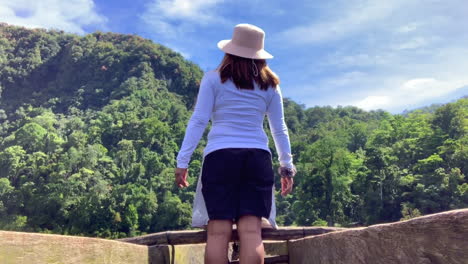 Footage-of-a-lady-standing-on-a-wooden-boat-facing-the-forest-as-she-embrace-the-nature's-beauty
