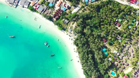 Wunderschöne-Türkisfarbene-Bucht-Mit-Ruhigem,-Klarem-Wasser,-Verankerten-Booten-In-Der-Nähe-Eines-Weißen-Exotischen-Strandes-Und-Von-Palmen-Umgebenen-Resort-Bungalows,-Thailand
