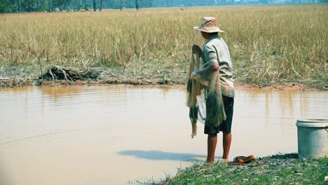 Fisherman-at-the-Edge-of-River-Readying-His-Net-Looking-Around-To-Select-The-Right-Place-Then-Walking-into-the-River