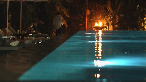 Medium-Exterior-Shot-of-People-Relaxing-and-Taking-Photos-at-Pool-Side-at-Night