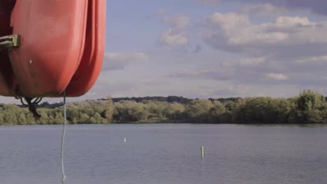 Red-safety-life-buoy-on-edge-of-large-lake-of-water