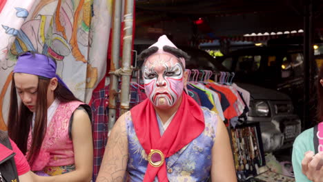 Ein-Taiwanesischer-Mann-Mit-Gesichtsbemalung-Kaut,-Während-Er-Während-Der-Taoistischen-Prozession-In-Taiwan-In-Die-Kamera-Starrt-–-Vergrößerte-Aufnahme