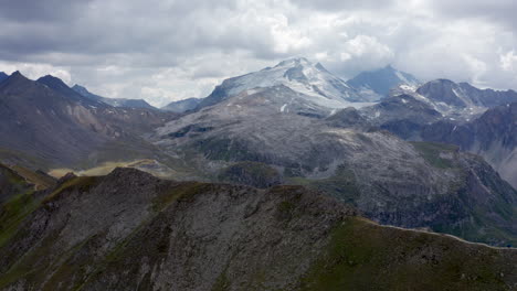 Drone-mountain-view-around-Tignes,-flying-over-a-ridge-with-La-Grande-Motte-glacier-on-the-back