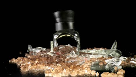 Slowly-pushing-towards-a-broken-sea-salt-grinder,-top-portion-standing-upright,-wide-angle-macro-view---showing-a-larger-portion-of-salt-throughout-and-some-of-the-broken-glass-intermingled