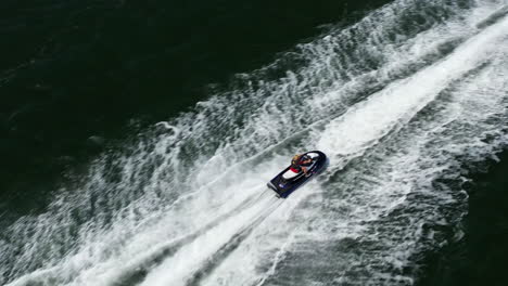 An-aerial,-dolly-shot-tracking-a-blonde-on-a-jet-ski-into-a-low-overhead-chase-from-behind