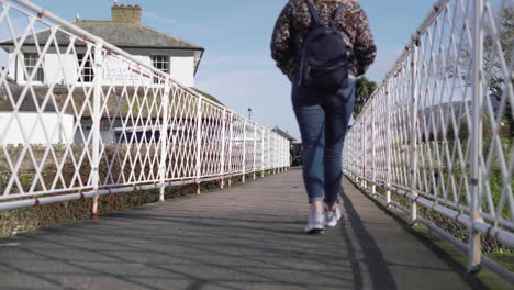 Woman-with-Backpack-Walking-Along-Metal-Bridge,-Low-Angle