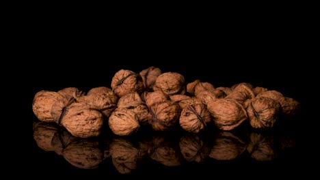 Walnuts-Falling-Into-a-Pile-of-More-Walnuts,-Black-Background
