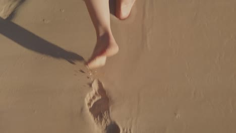 Eine-Nahaufnahme-Von-Frauenfüßen,-Die-Am-Strand-über-Den-Sand-Laufen,-Fußspuren-Hinterlassen-Und-Den-Sand-Trocknen