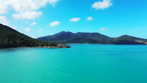 Das-Azurblaue-Meerwasser-Spiegelt-Den-Strahlend-Blauen-Himmel-Mit-Weißen-Wolken-über-Tropischen-Inseln-Mit-Grünen-Hügeln-In-Thailand-Wider