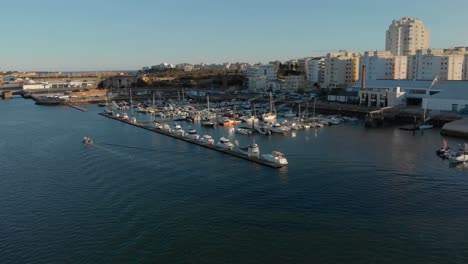 Antena-De-Barcos-Amarrados-En-El-Puerto-Deportivo-De-Portimao,-Algarve,-Portugal,-Horizonte-Y-Barco-Que-Viene