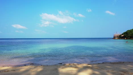 Friedliche-Meereslandschaft-Mit-Ruhigem,-Klarem-Wasser-Der-Flachen-Lagune-Im-Schatten-Von-Palmen,-Heller-Himmel-Mit-Gefrorenen-Weißen-Wolken,-Antigua